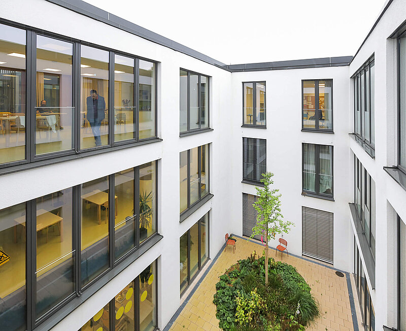 Innenhof eines dreistöckigen Klinikgebäudes mit vielen großen Fenstern.