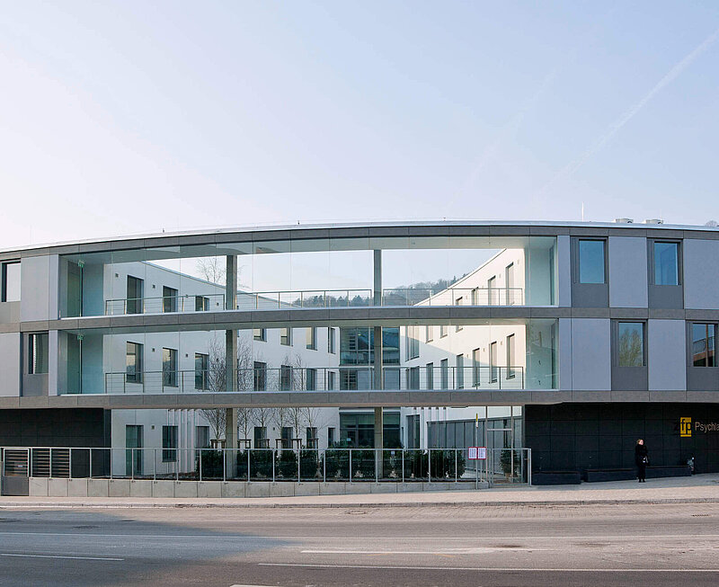 Sicht auf das moderne dreistöckige psychiatrische Behandlungszentrum Waldshut-Tiengen. Vorne führt eine mehrspurige Straße vorbei.